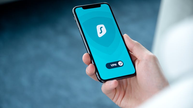 A hand holding a smartphone displaying a VPN app screen for secure online browsing
