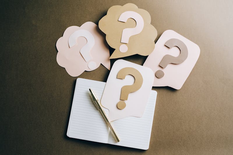 Flat lay of question mark paper crafts on a notebook, symbolizing questions and ideas